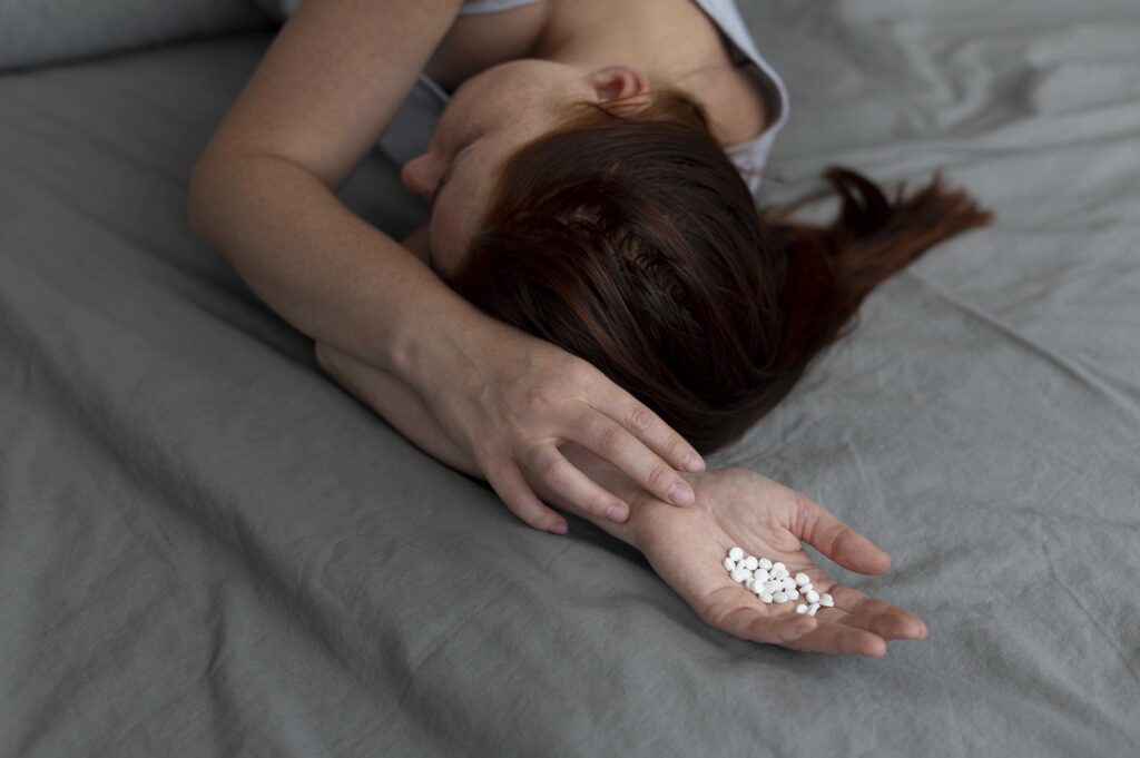 woman on bed with sleeping pills in her hands