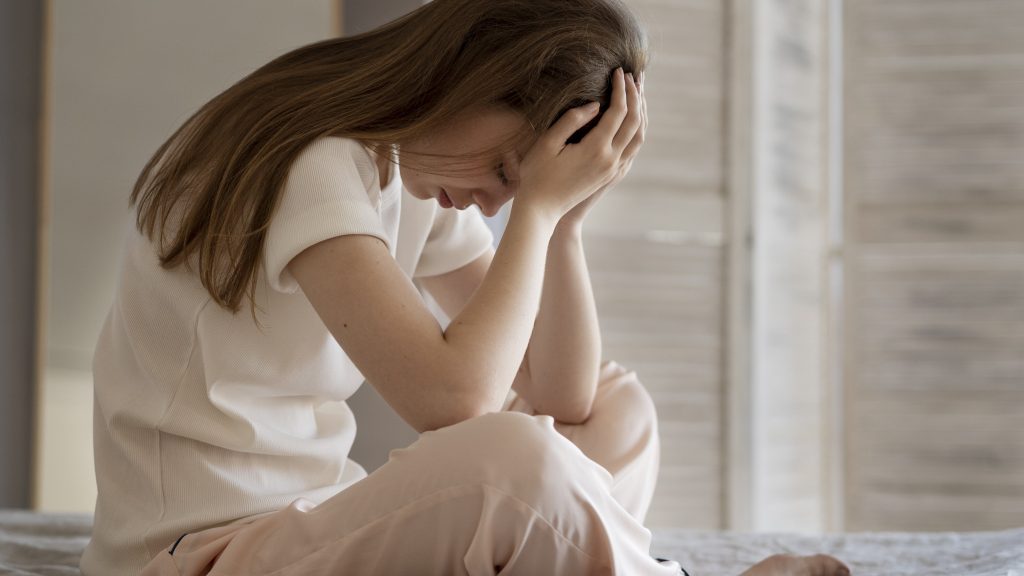 sad woman sitting indoors representing the distress of sleep anxiety