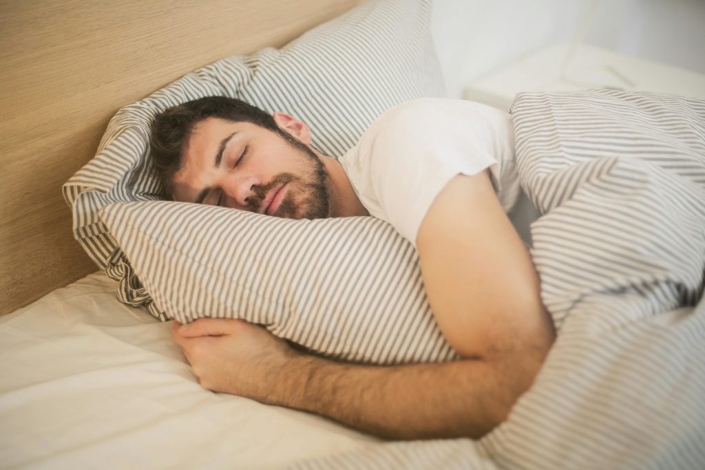 man sleeping peacefully in bed on a pillow and quilt