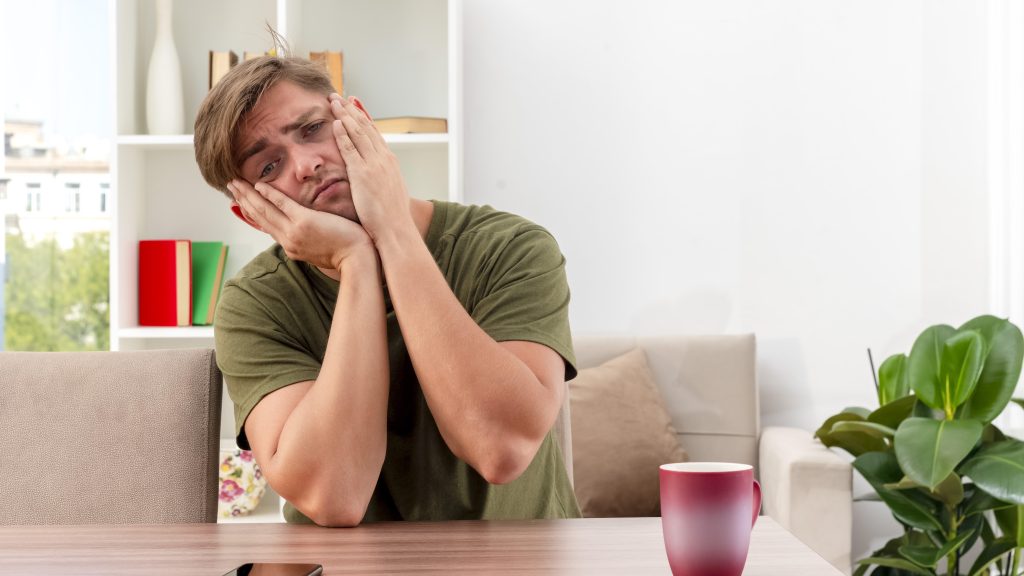 tired man sitting at a table with a mug illustrating the need for act sleep therapy