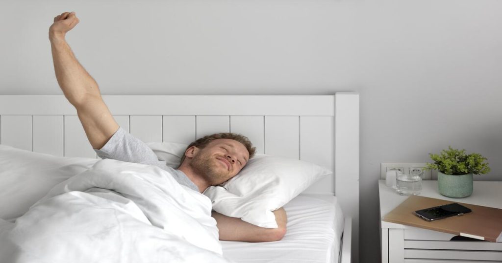 man happily stretching in bed after a restful night showing the success of act sleep therapy
