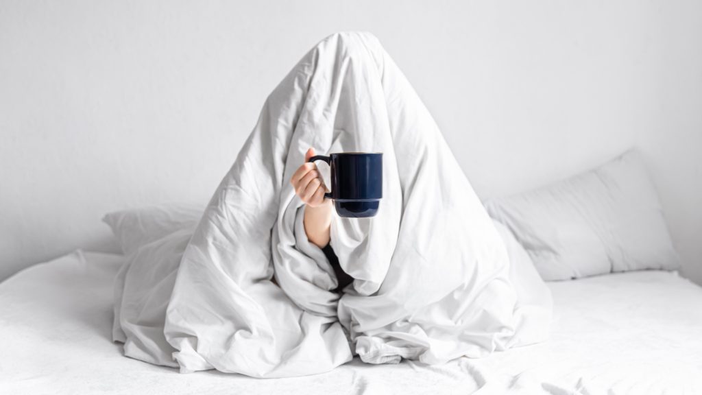 person wrapped in a white duvet illustrating choice between sleeping pills and natural sleep aids