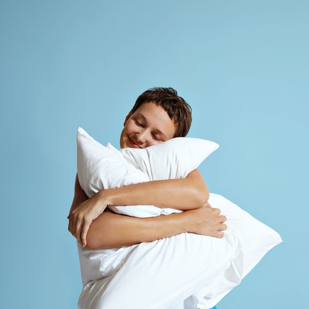 happy woman hugging pillows as a result of sleep therapy cbt and act for insomnia