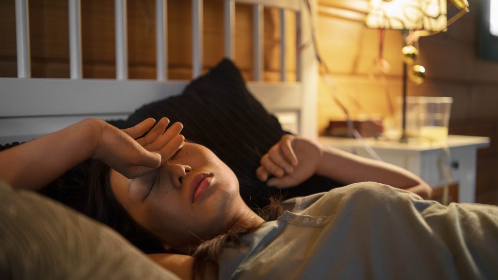 frustrated asian woman lying in bed unable to sleep illustrating the psychological struggles managed by act sleep therapy