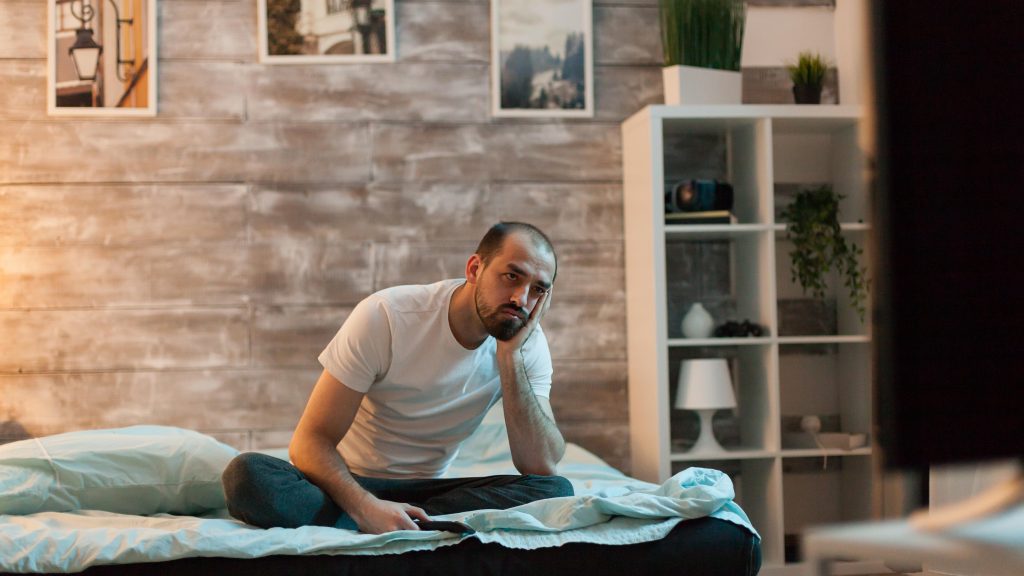 man sitting on his bed suffering from sleep problems due to adhd