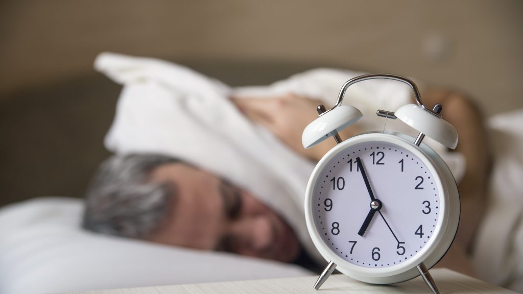 man sleeping with clock visible on the table