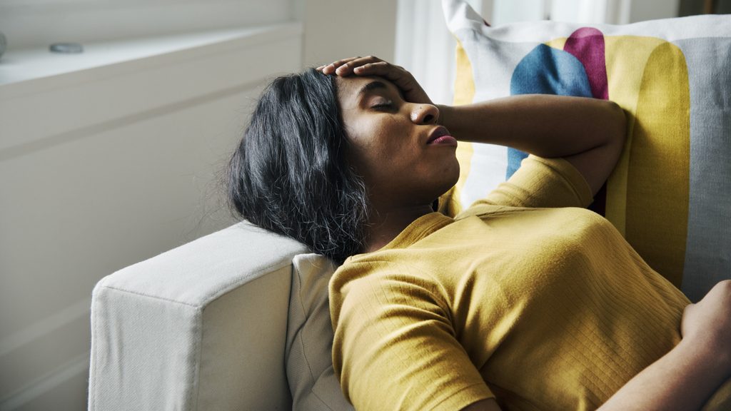 tired woman resting with her hand on her forehead experiencing daytime fatigue and sleep deprivation from menopausal insomnia