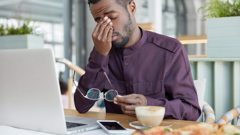 a remote worker experiencing eye strain and daytime fatigue from sleep disruption