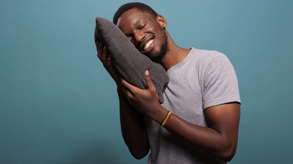 relaxed man hugging a pillow illustrating supportive conditions for better rest and natural sleep during winter 