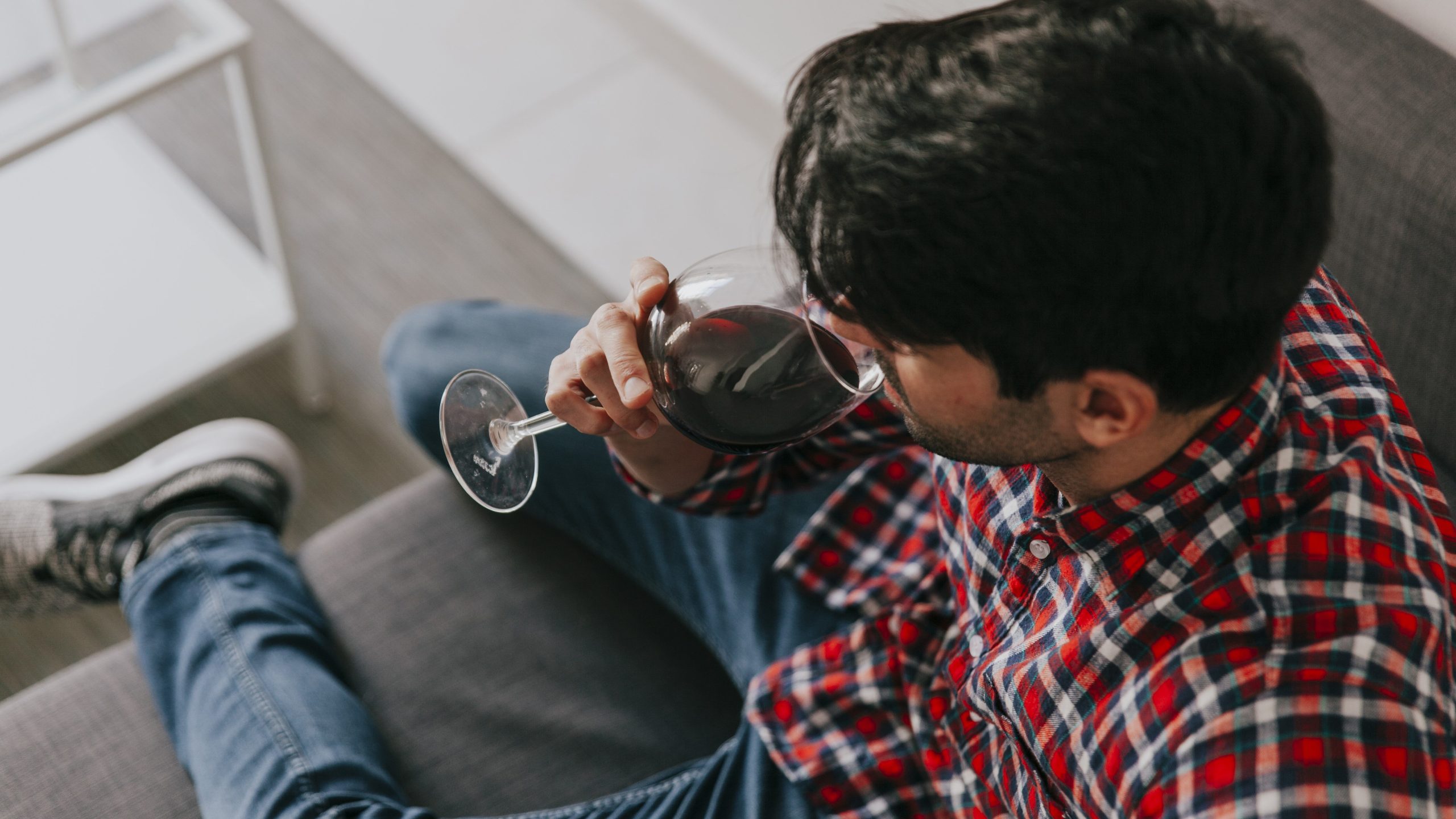 man drinking a glass of wine to wind down using alcohol as a shortcut to fall asleep