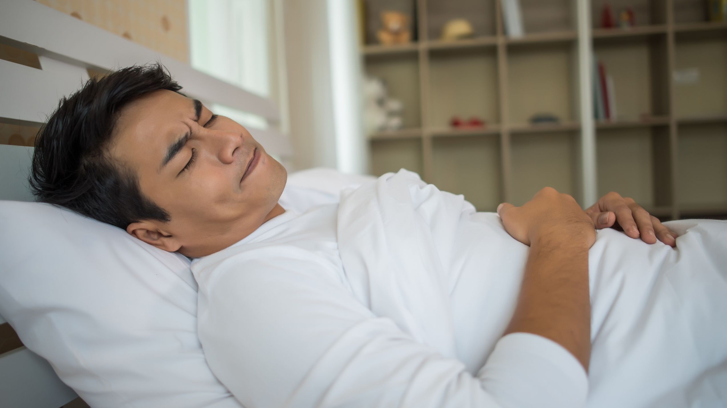 man asleep in bed with furrowed brow illustrating somatic grounding needs