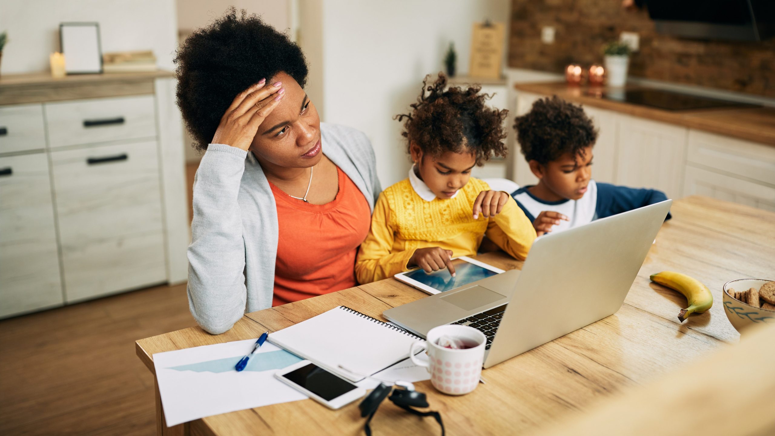 exhausted working mother sitting with laptop and children representing stress and insomnia in working moms